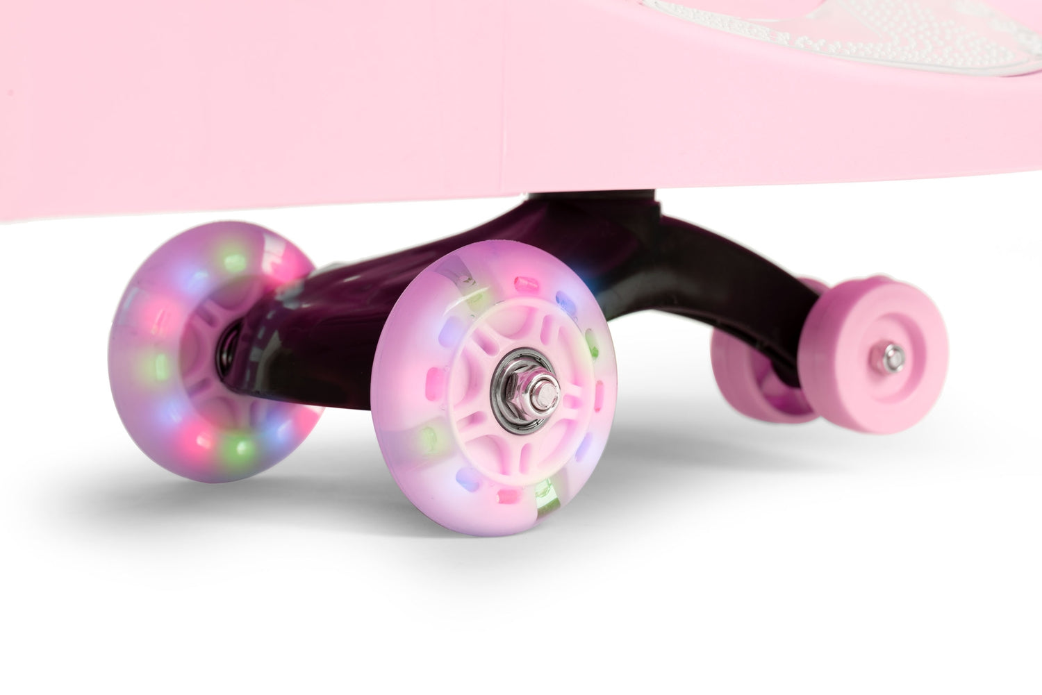 Primer plano de las ruedas de un patinete rosa. Dos ruedas delanteras tienen luces de colores y una rueda rosa a la derecha.