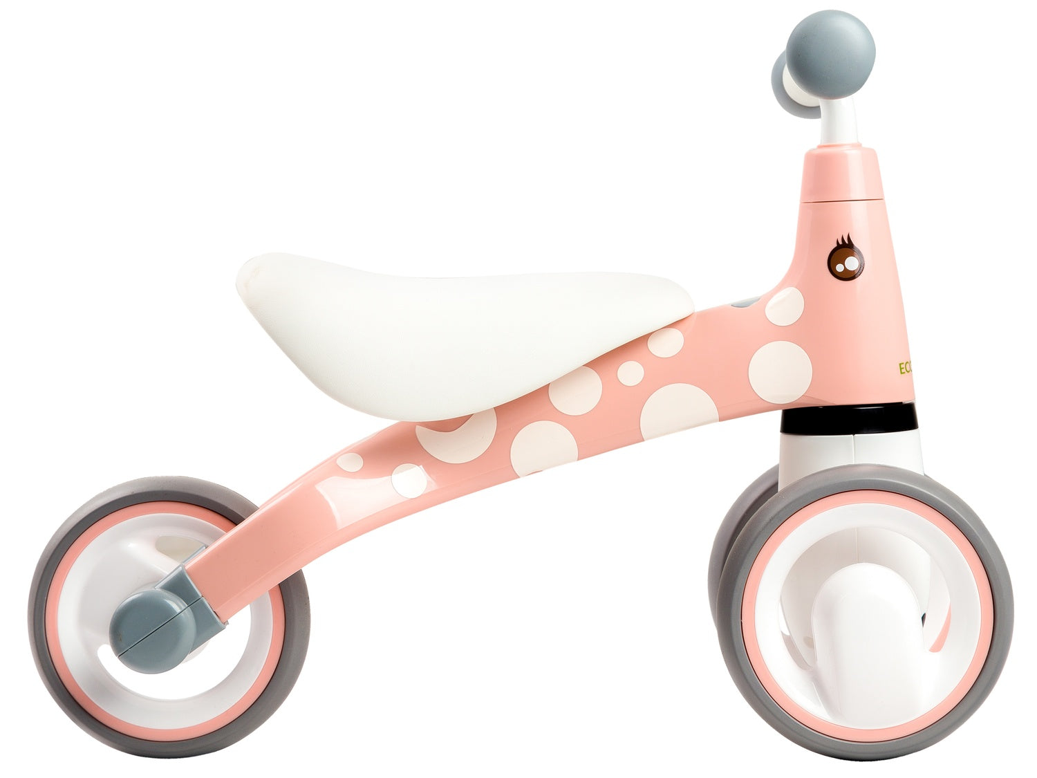 Bicicletta senza pedali rosa e bianca a pois per bambini. Ha un sedile bianco, ruote grigie e un design a forma di giraffa.