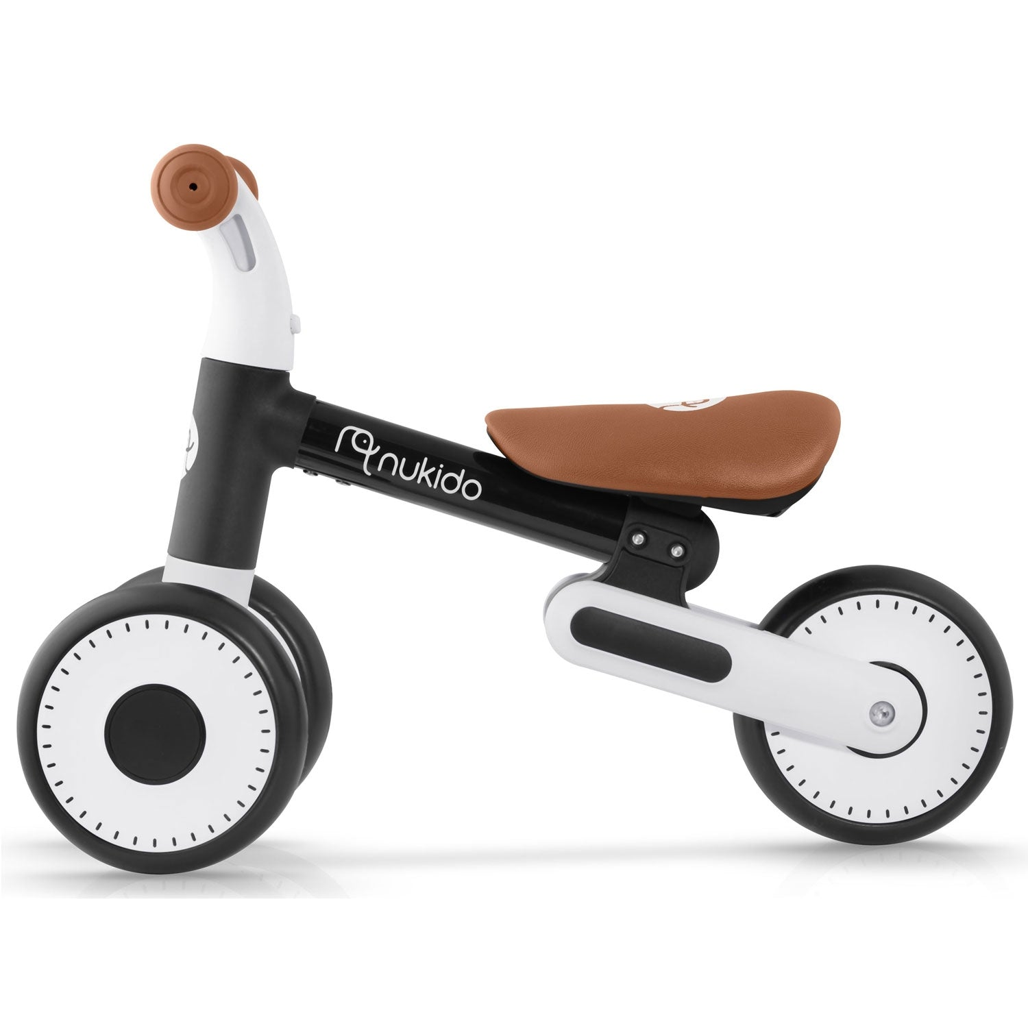 Una bicicleta de equilibrio con asiento y manillar marrones. Tiene partes negras y blancas. Las ruedas tienen detalles blancos y negros.