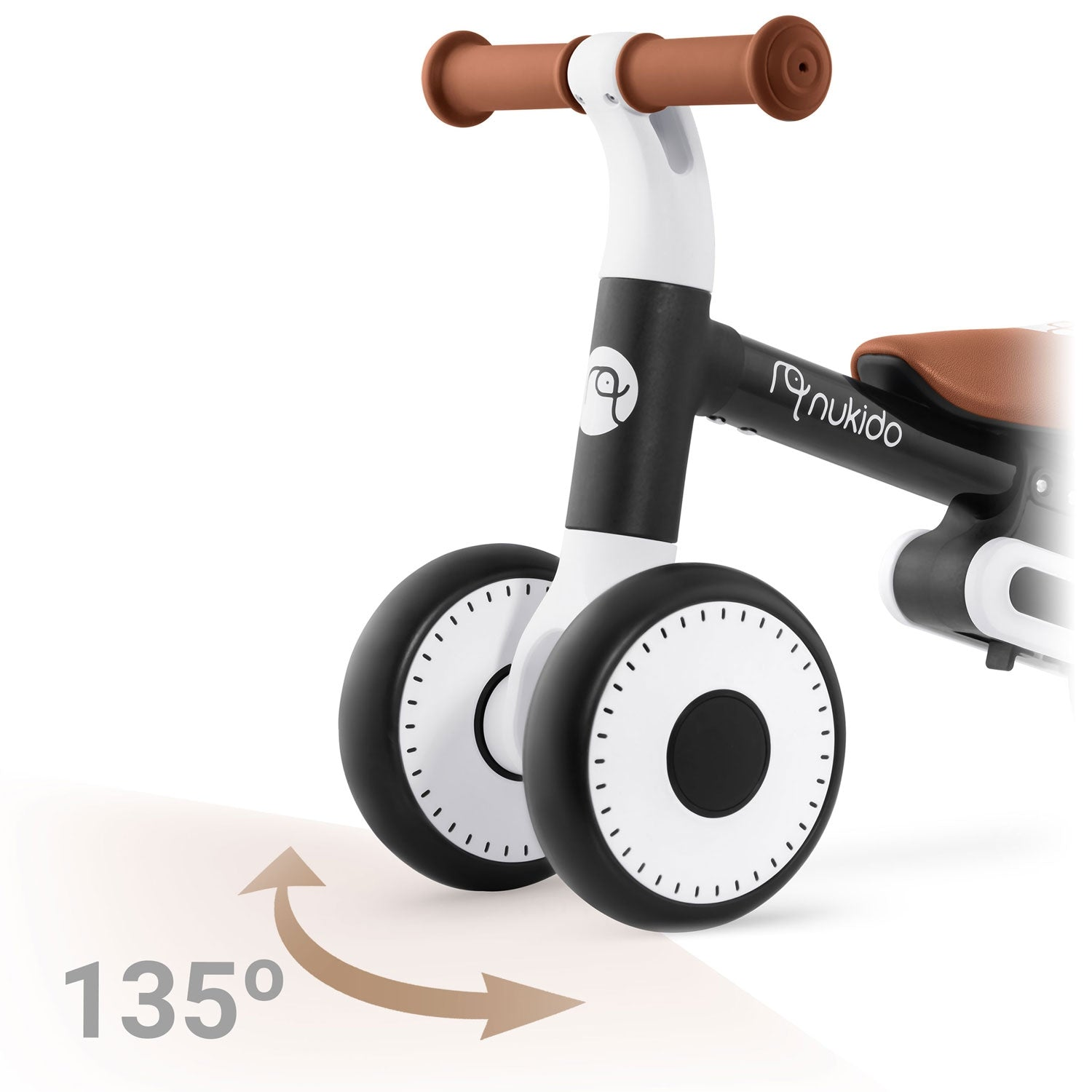 Una bicicleta de equilibrio con un marco negro y blanco, manijas marrones y un asiento marrón. Las ruedas son negras con centros blancos. Se muestra una flecha de 135 grados.