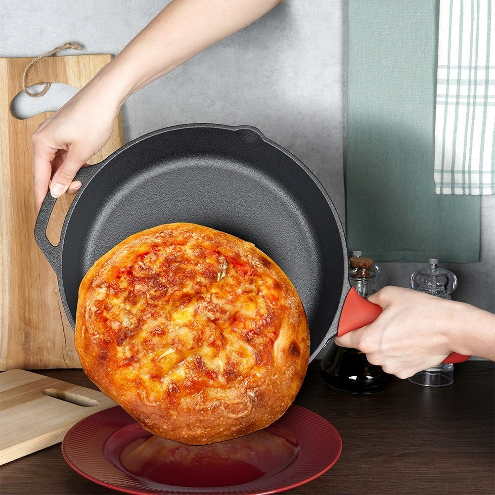 Eine Person hält eine gusseiserne Pfanne mit einer gebackenen Pizza. Darunter steht ein roter Teller. Schneidebretter und ein Handtuch im Hintergrund.