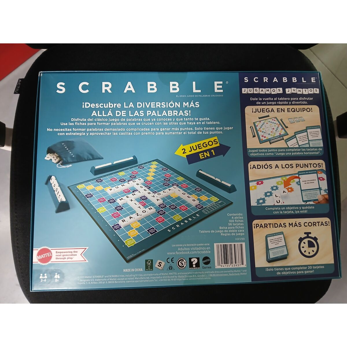 Juego de mesa Scrabble en una silla negra. La caja muestra el tablero, fichas e instrucciones, con texto en español.