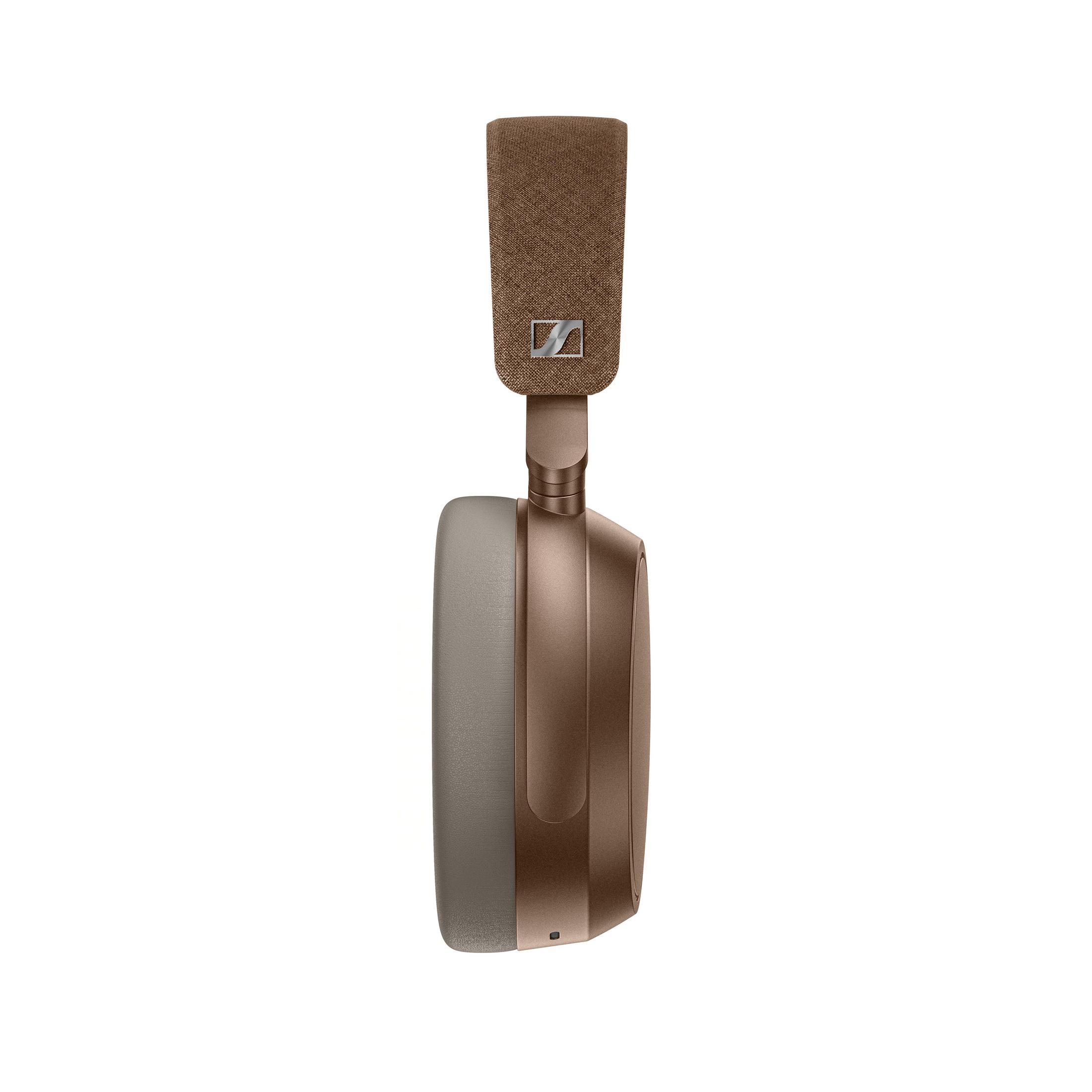 Ein brauner und hellbrauner Over-Ear-Kopfhörer. Das Kopfband ist aus braunem Stoff. Die Ohrmuscheln sind hellbraun und braun. Weißer Hintergrund.