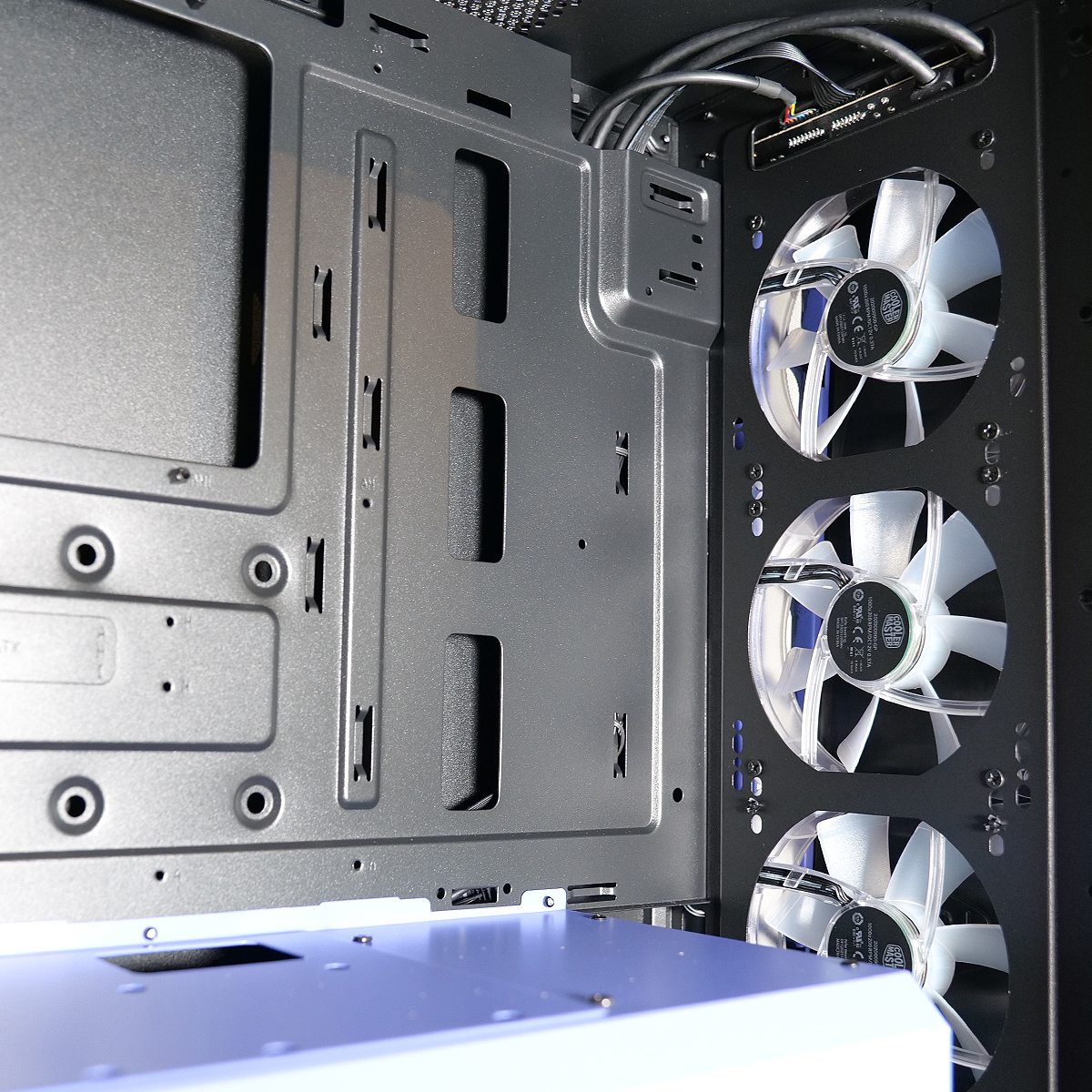 All'interno di un case per computer, sono visibili tre ventole bianche. Sono visibili anche pannelli metallici grigi con fori di montaggio e cablaggio.