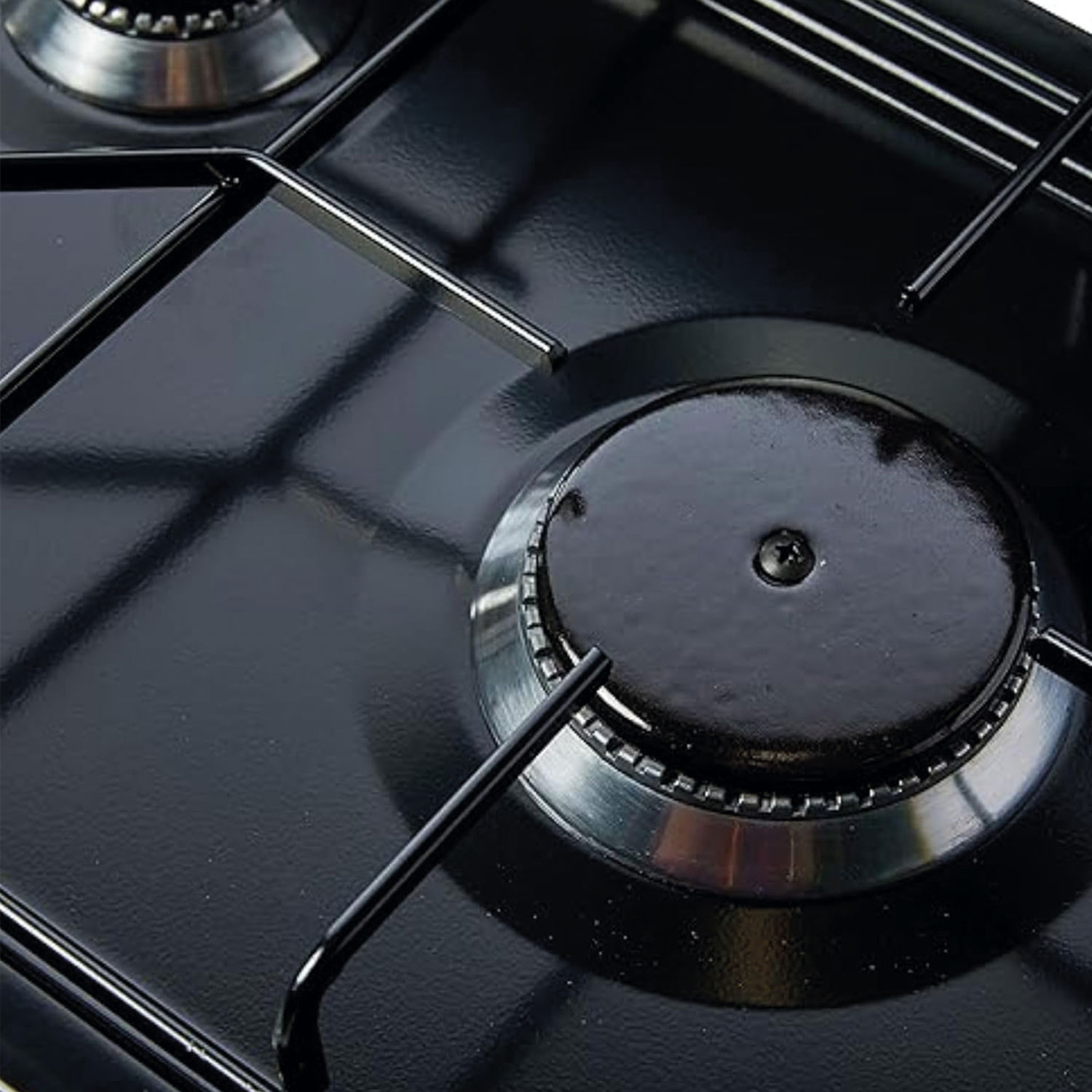 Primer plano de un quemador de estufa de gas negro. Anillo de acero inoxidable alrededor del quemador con soportes metálicos negros y superficie negra.