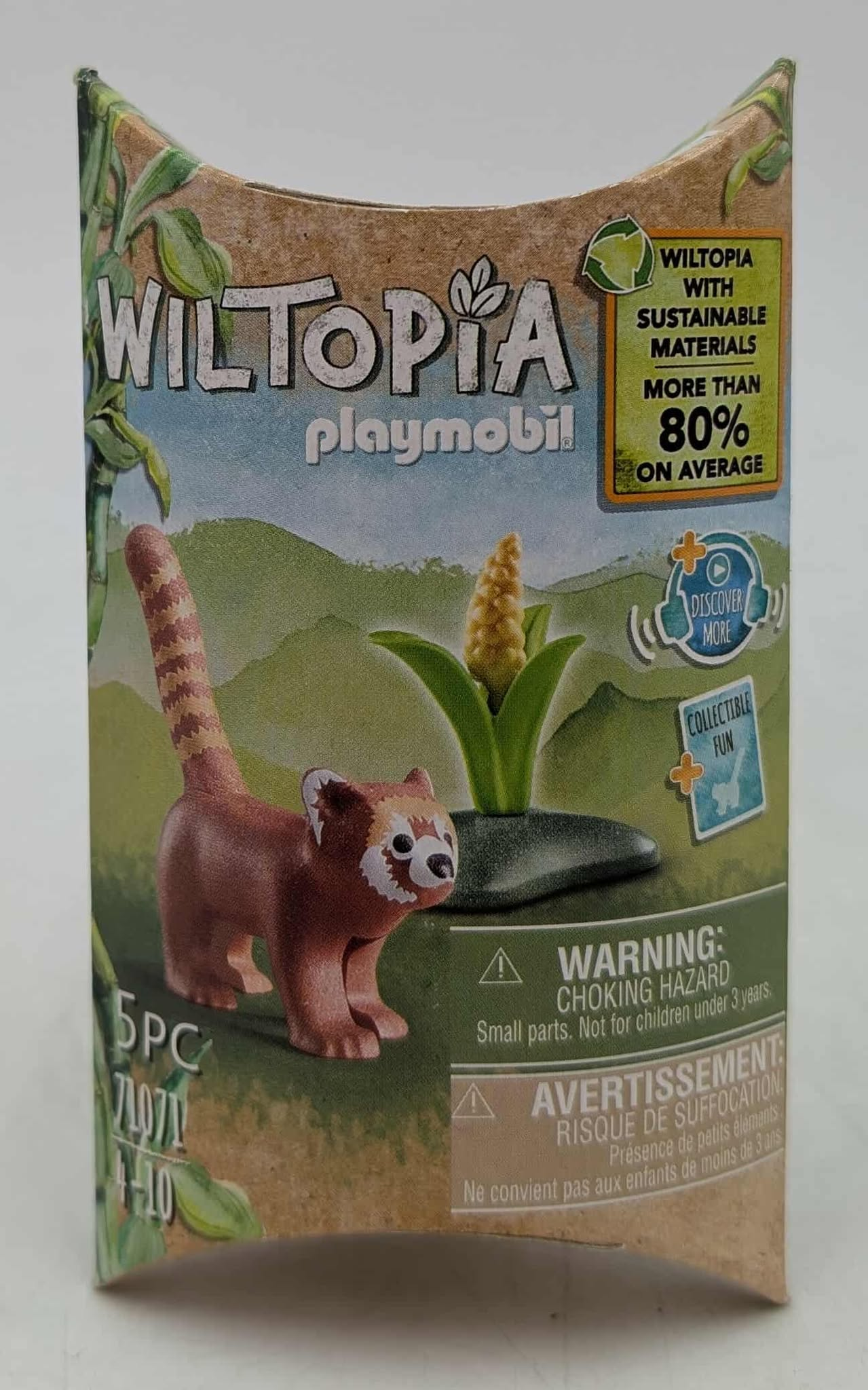 A Playmobil box with a red panda figure. It says WILTOPIA and has warning labels. The background shows a green landscape.