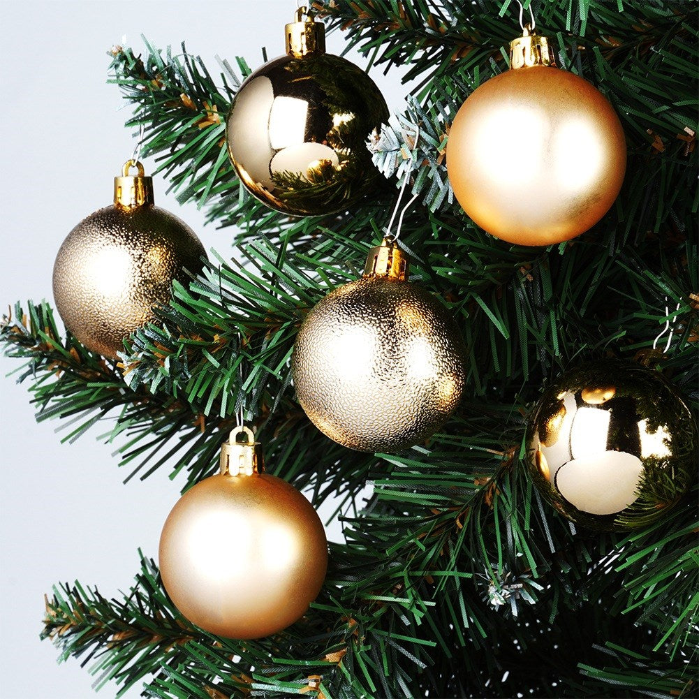 Primer plano de un árbol de Navidad con seis adornos dorados. Los adornos tienen diferentes texturas y cuelgan de ramas verdes.