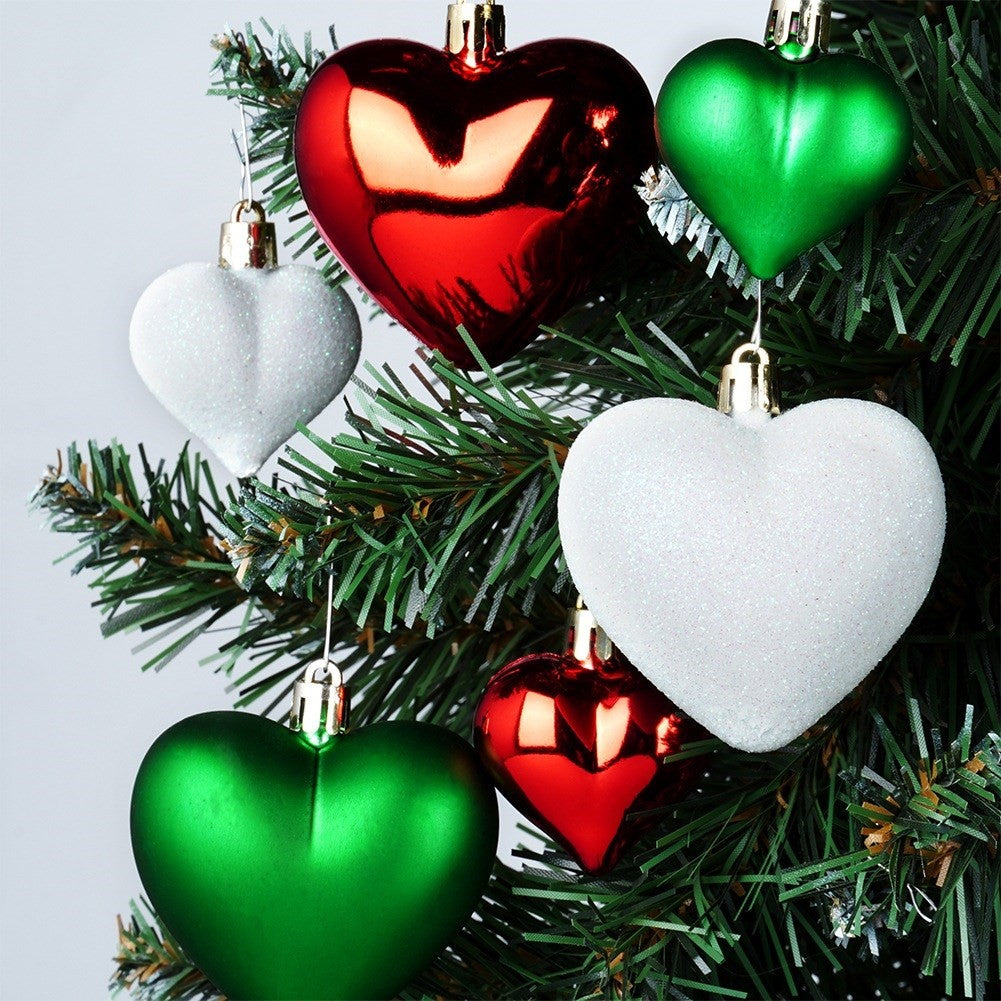 Árbol de Navidad con adornos en forma de corazón. Adornos rojos, blancos y verdes cuelgan del árbol. El fondo es blanco.