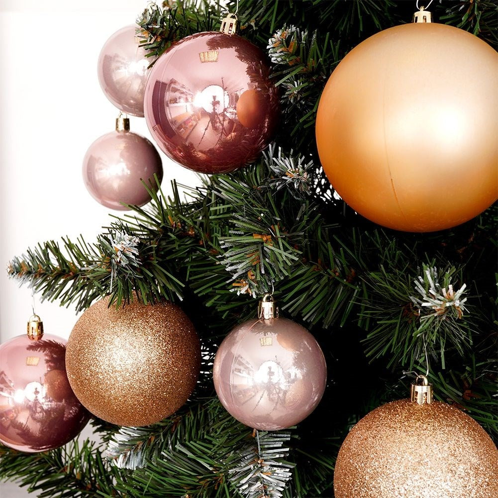Un árbol de Navidad decorado con varios adornos. Los adornos son de diferentes colores, incluyendo dorado, oro rosa y rosa.