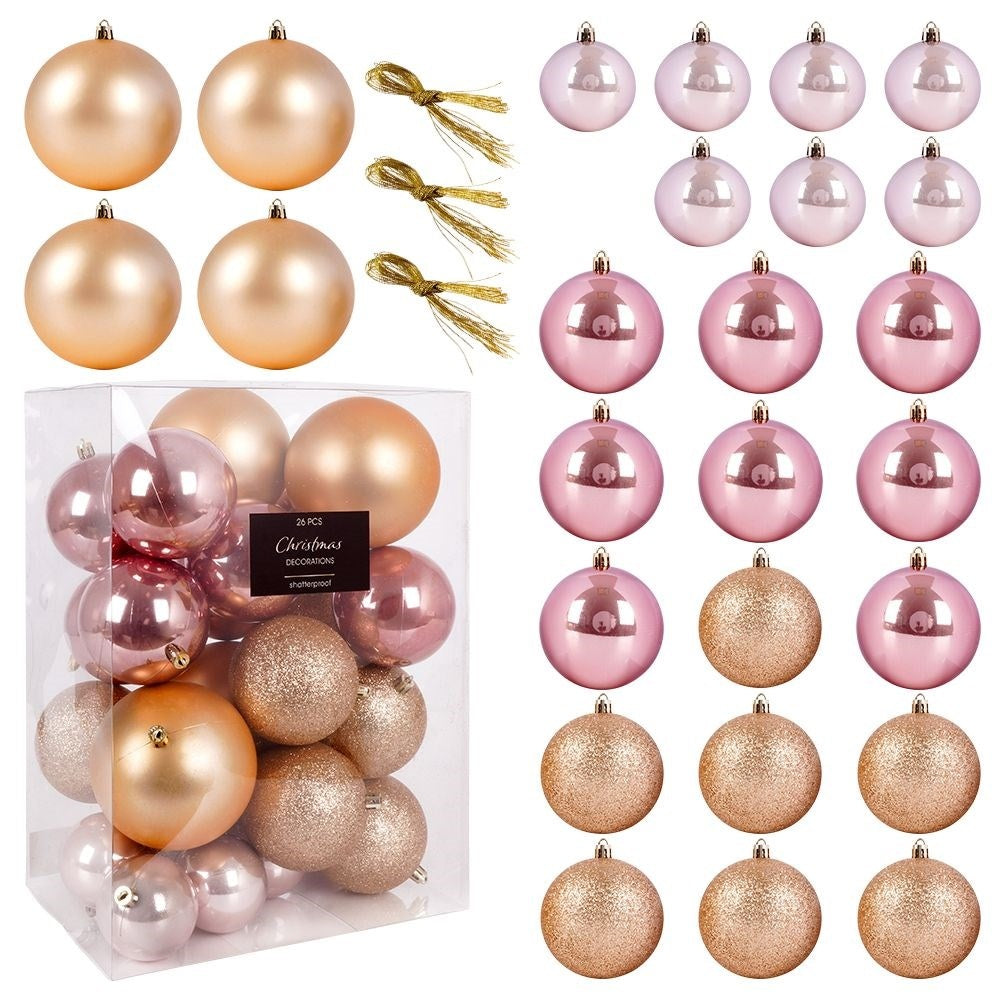 Varios adornos navideños. Algunos son dorados, rosas y brillantes. Algunos están en una caja transparente. También hay cintas doradas.