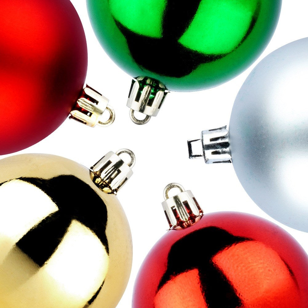 Primer plano de cinco adornos navideños. Los colores incluyen rojo, dorado, verde y plateado, sobre un fondo blanco.