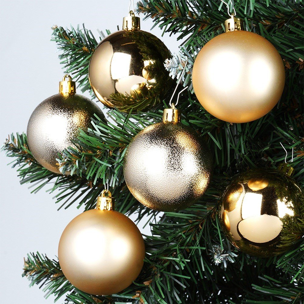 Primer plano de un árbol de Navidad con seis adornos dorados. Los adornos son de diferentes tonos dorados, con texturas variadas.