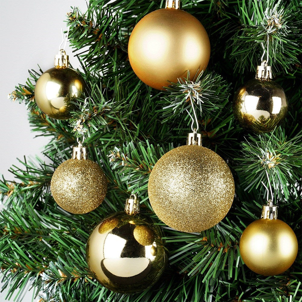 Primer plano de un árbol de Navidad con adornos dorados. Algunos son lisos, otros brillantes. El árbol tiene agujas verdes y un fondo blanco.