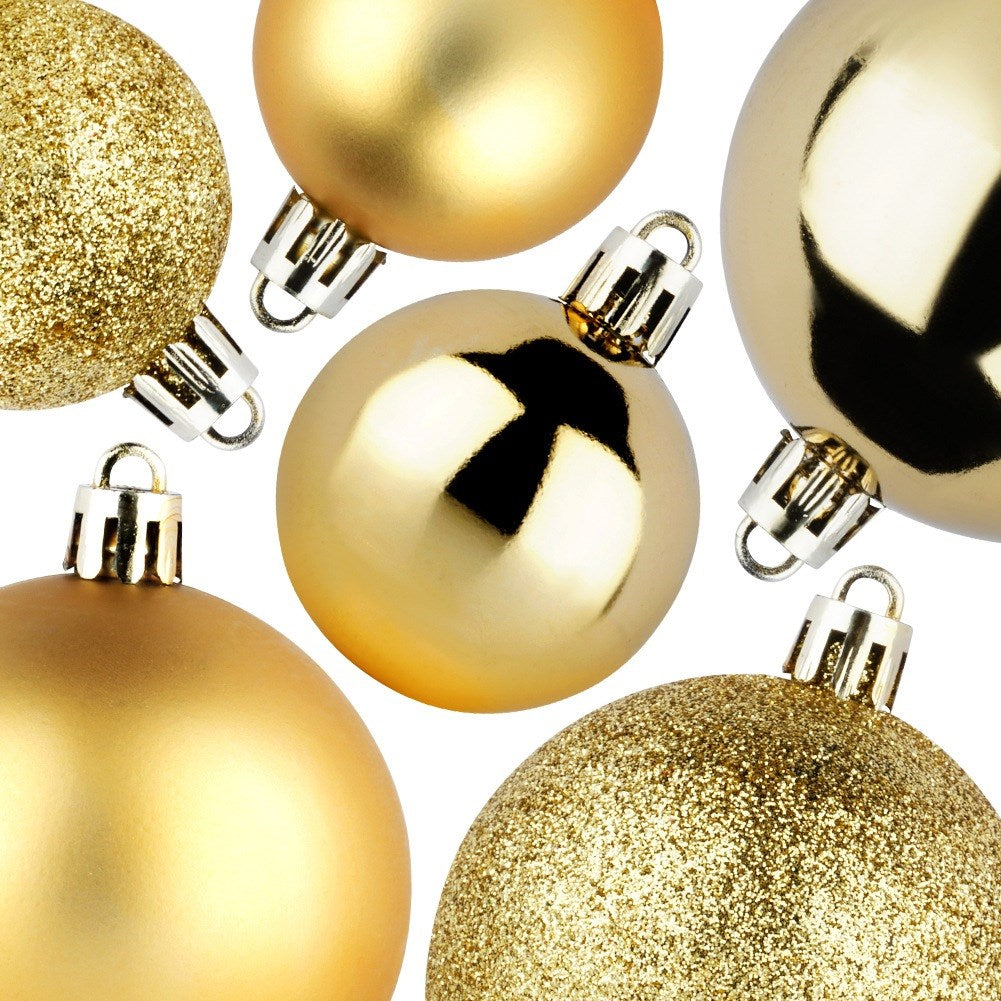 Primer plano de adornos navideños dorados con diferentes texturas. Algunos son brillantes, otros brillantes, sobre un fondo blanco.