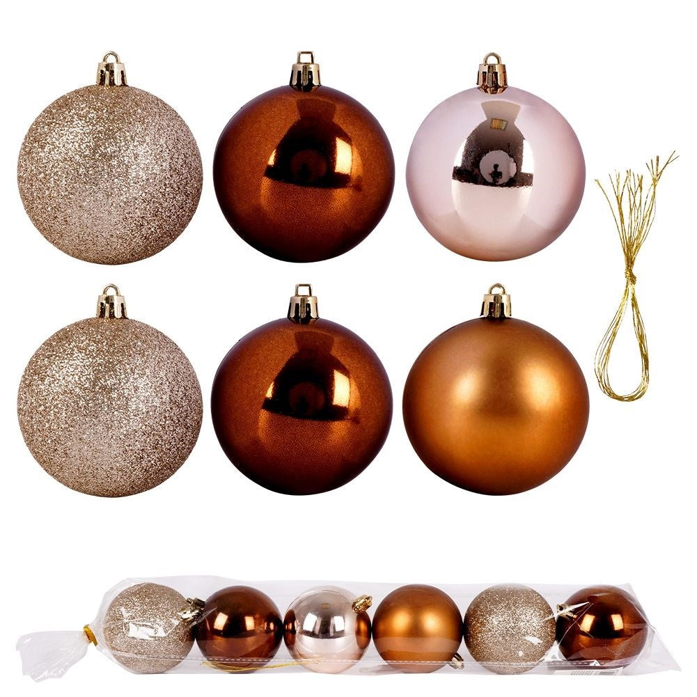 Varios adornos navideños: dorados, marrones y rosas, algunos brillantes. Se ve un pequeño manojo de hilo dorado. Los adornos están en una bolsa de plástico transparente.