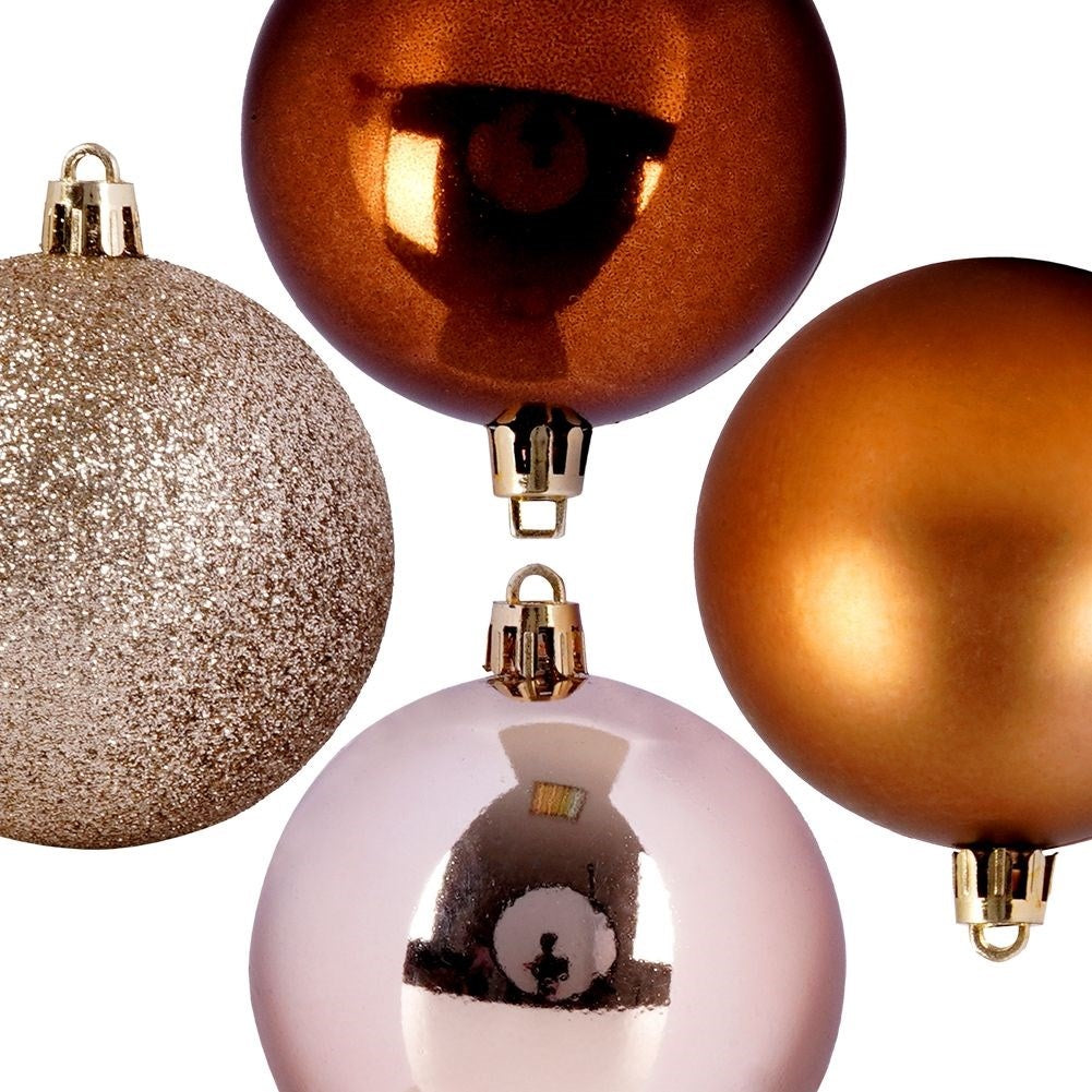 Cuatro adornos navideños: purpurina dorada, bronce, oro y rosa. Cada uno tiene una tapa dorada. El fondo es blanco.