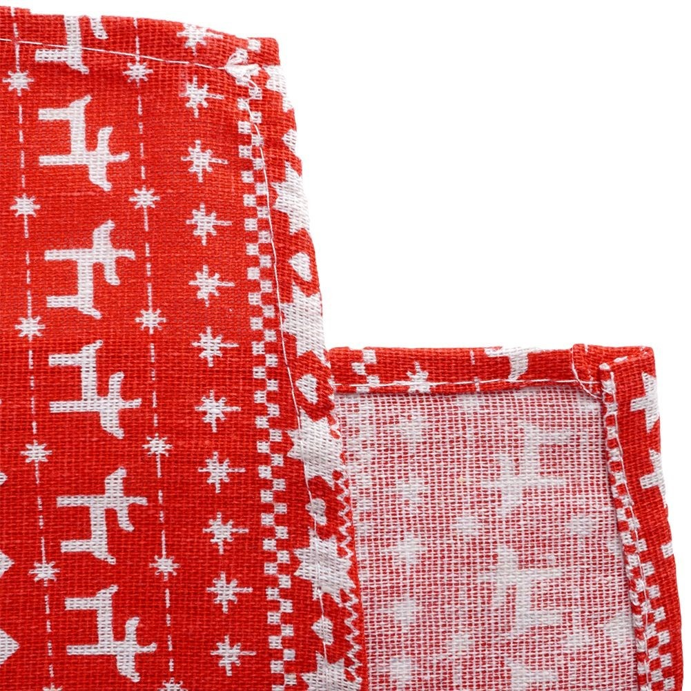 Primer plano de una tela roja con un patrón blanco de copos de nieve y árboles de Navidad. La tela tiene un borde doblado.