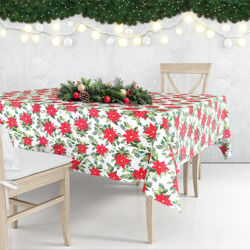 Una mesa navideña con mantel de flor de Pascua, guirnalda festiva y sillas. El fondo muestra luces y una pared.
