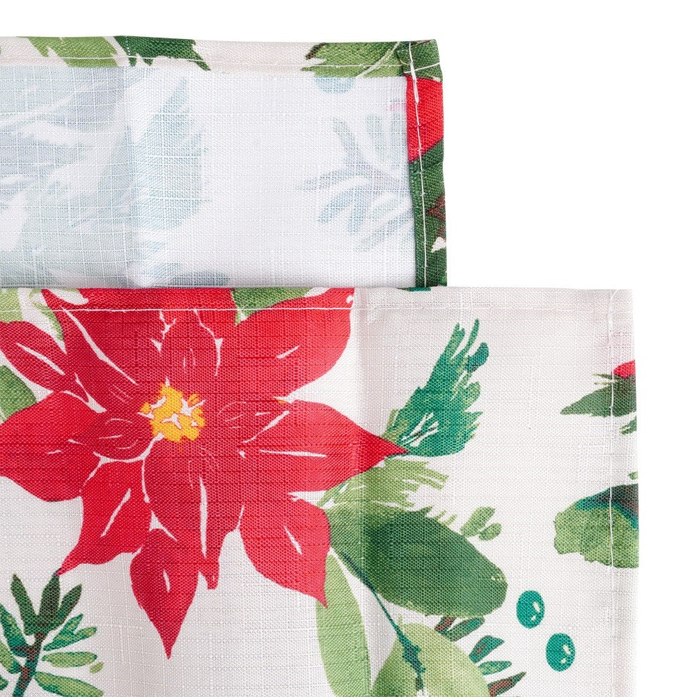 Primer plano de una tela festiva. Flor de pascua roja, hojas verdes y fondo blanco. La tela está doblada y cosida.