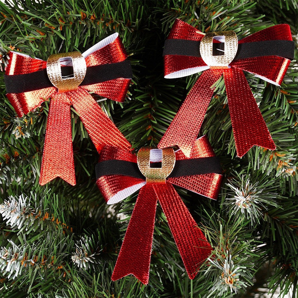 Tres lazos navideños rojos con rayas blancas y negras y hebillas doradas sobre un árbol de Navidad verde.