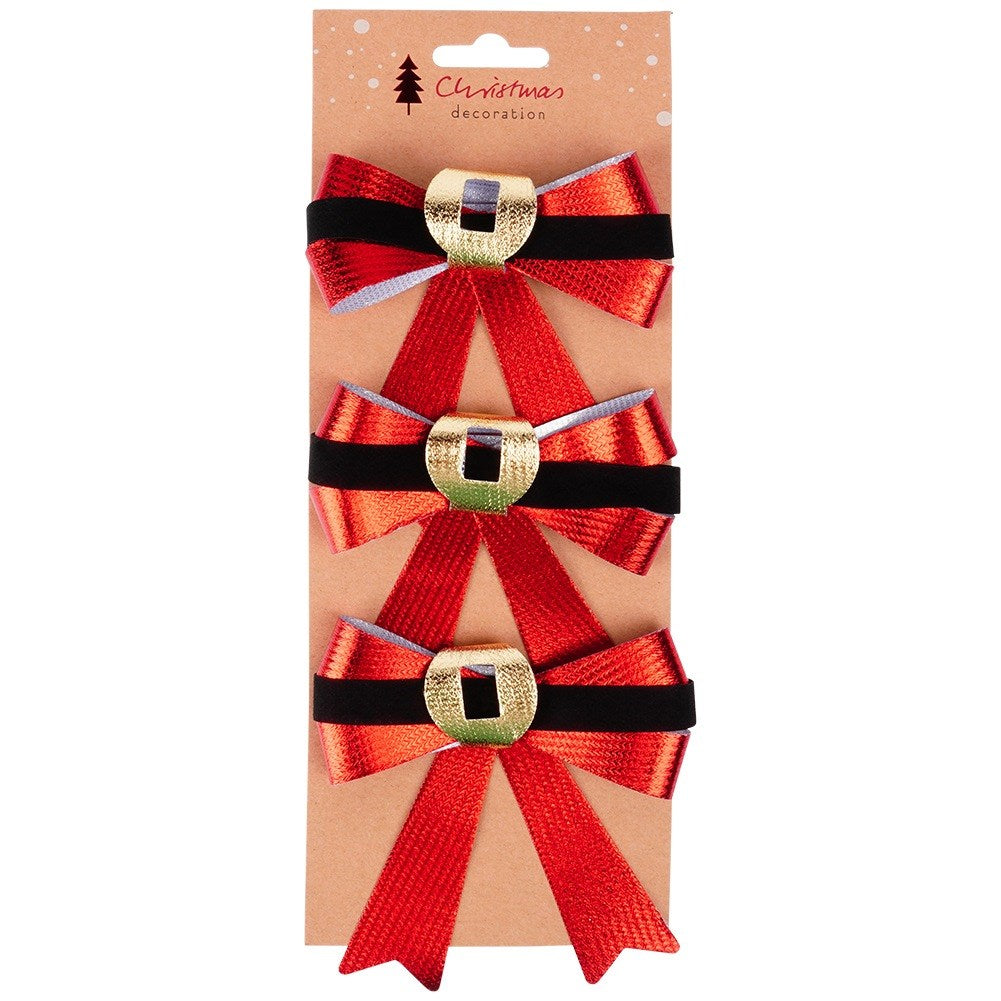 Tres lazos rojos navideños con hebillas doradas y bandas negras, dispuestos verticalmente sobre una tarjeta marrón.