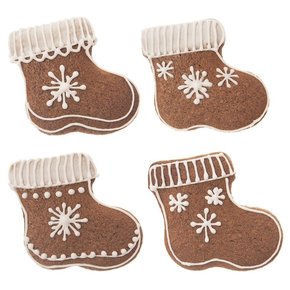 Cuatro galletas de jengibre con glaseado blanco. Cada una tiene un diseño de copo de nieve y borde blanco. Aisladas sobre fondo blanco.