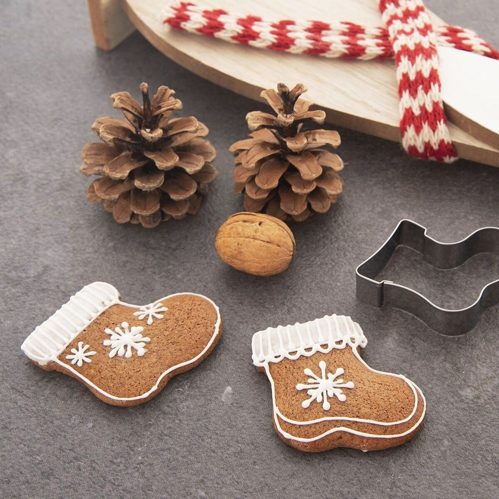 Decoración navideña: galletas, piñas, nueces, cortadores de galletas en forma de bota y una bufanda en un trineo de madera.
