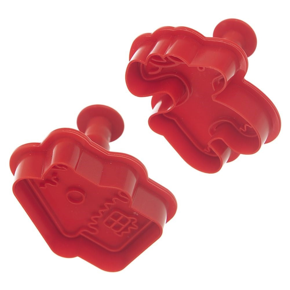 Dos cortadores de galletas rojos en forma de casa sobre un fondo blanco. Cada cortador tiene un mango. Uno está inclinado hacia abajo a la izquierda.