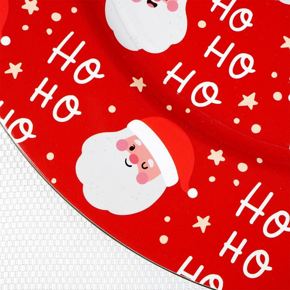 Un plato rojo navideño con caras de Santa, texto 'Ho Ho Ho', estrellas y puntos blancos. El borde del plato es visible.