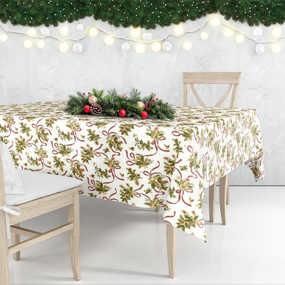 Una mesa está lista para Navidad. Un mantel blanco con estampado de acebo. Un centro de mesa de abeto, adornos y luces.