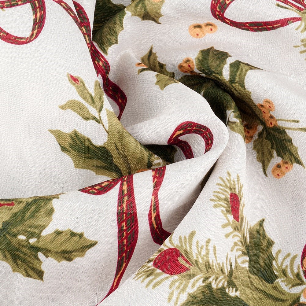 Tela blanca con hojas verdes, bayas rojas y lazos. El diseño es navideño. La tela está arrugada.