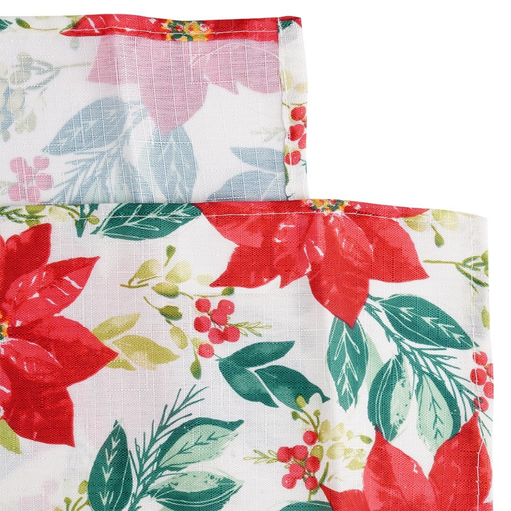 Primer plano de una tela blanca con poinsettias rojas, hojas verdes y bayas rojas. El borde superior tiene un diseño rojo y floral.