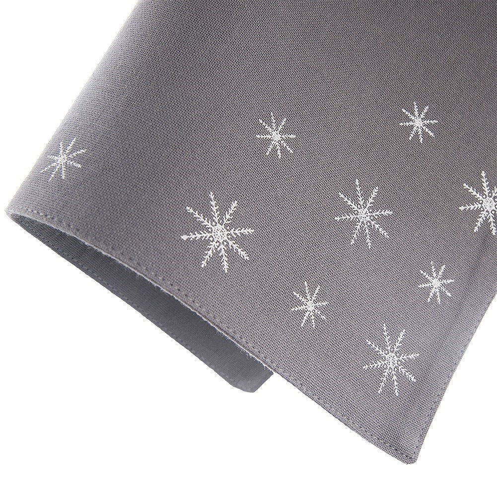 Una tela gris con patrones de copos de nieve blancos. La tela está doblada, mostrando ambos lados. Los copos de nieve están espaciados.