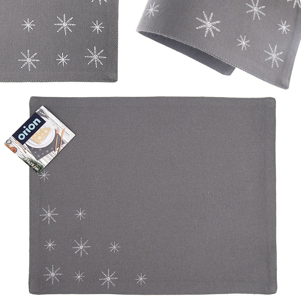 Mantel individual gris con diseños de copos de nieve blancos. Hay una etiqueta del producto en la esquina. Hay otras dos piezas de la misma tela.