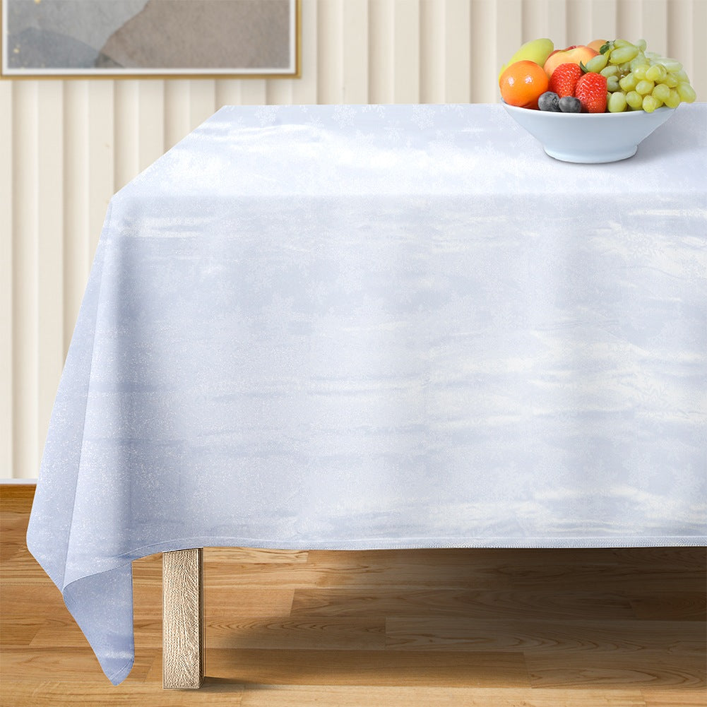Una mesa cubierta con un mantel blanco tiene un cuenco de fruta. El fondo muestra una pintura y una pared.