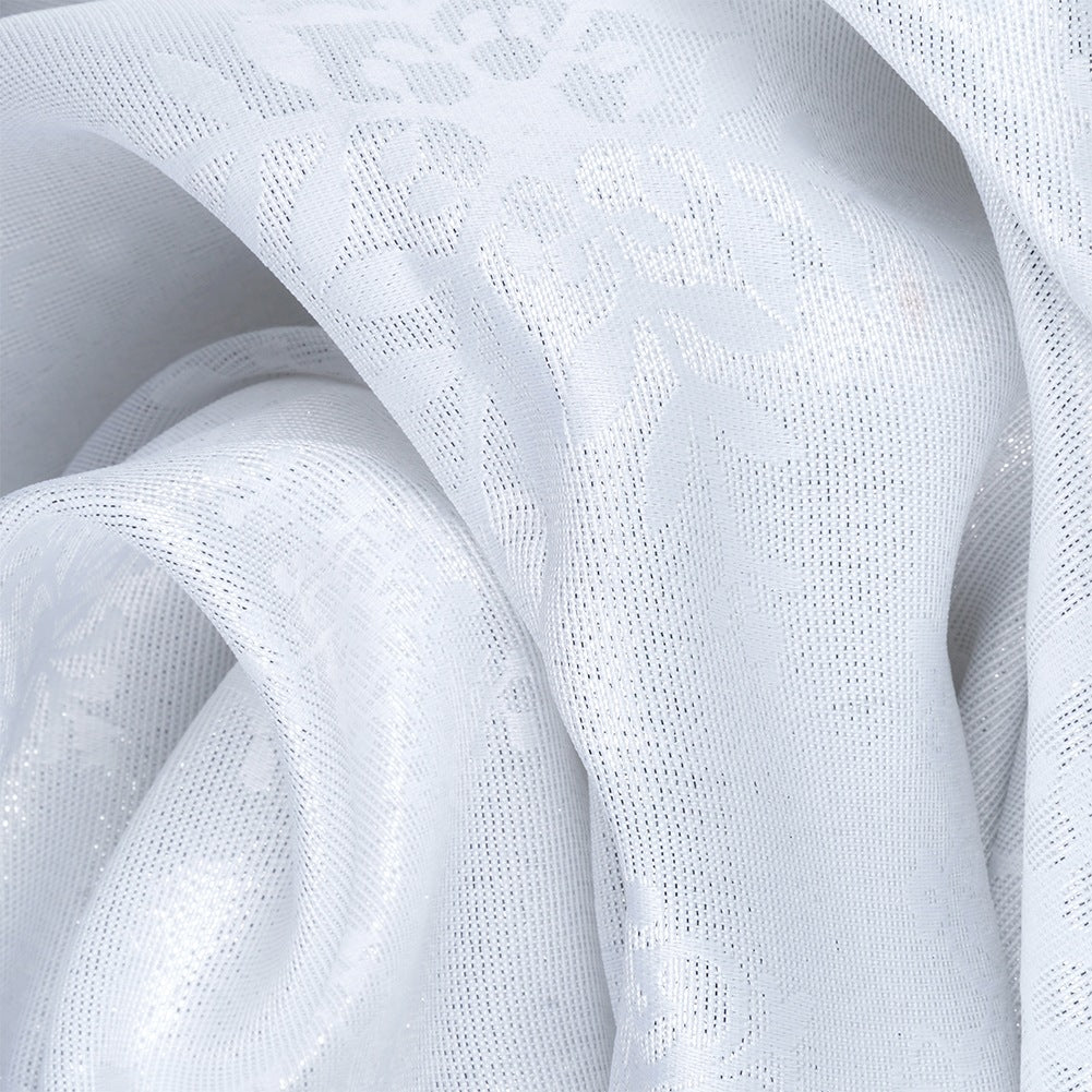 Primer plano de tela blanca y fluida con un patrón floral. La tela es texturizada y en capas, creando sombras y reflejos.