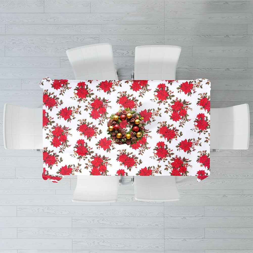 Vista aérea de una mesa navideña. Poinsettias rojas en el mantel, una corona en el centro y sillas blancas alrededor.