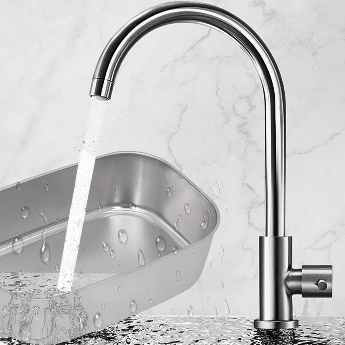 Ein Wasserhahn aus Edelstahl gießt Wasser in ein Metallbecken. Wassertropfen sind auf dem Becken und im Hintergrund sichtbar.