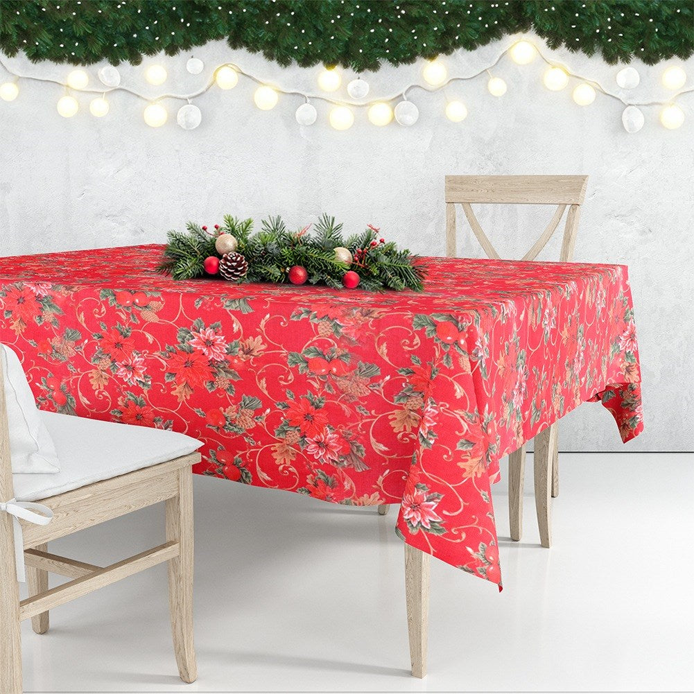 Una mesa festiva está puesta con un mantel rojo floral, decorado con un centro de mesa y luces.