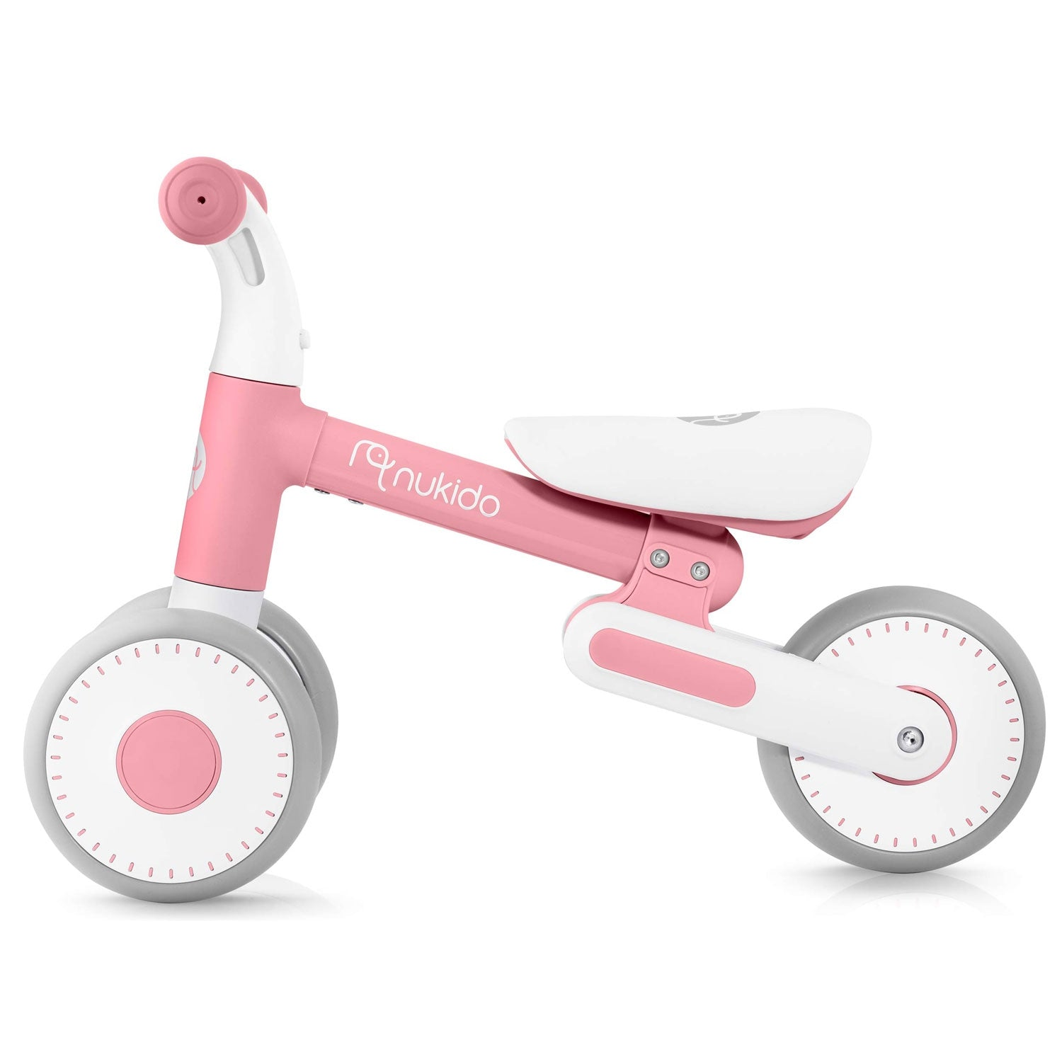 Una bicicleta de equilibrio Nukido rosa y blanca para niños pequeños. La bicicleta tiene dos ruedas, un asiento, un manillar y la marca.