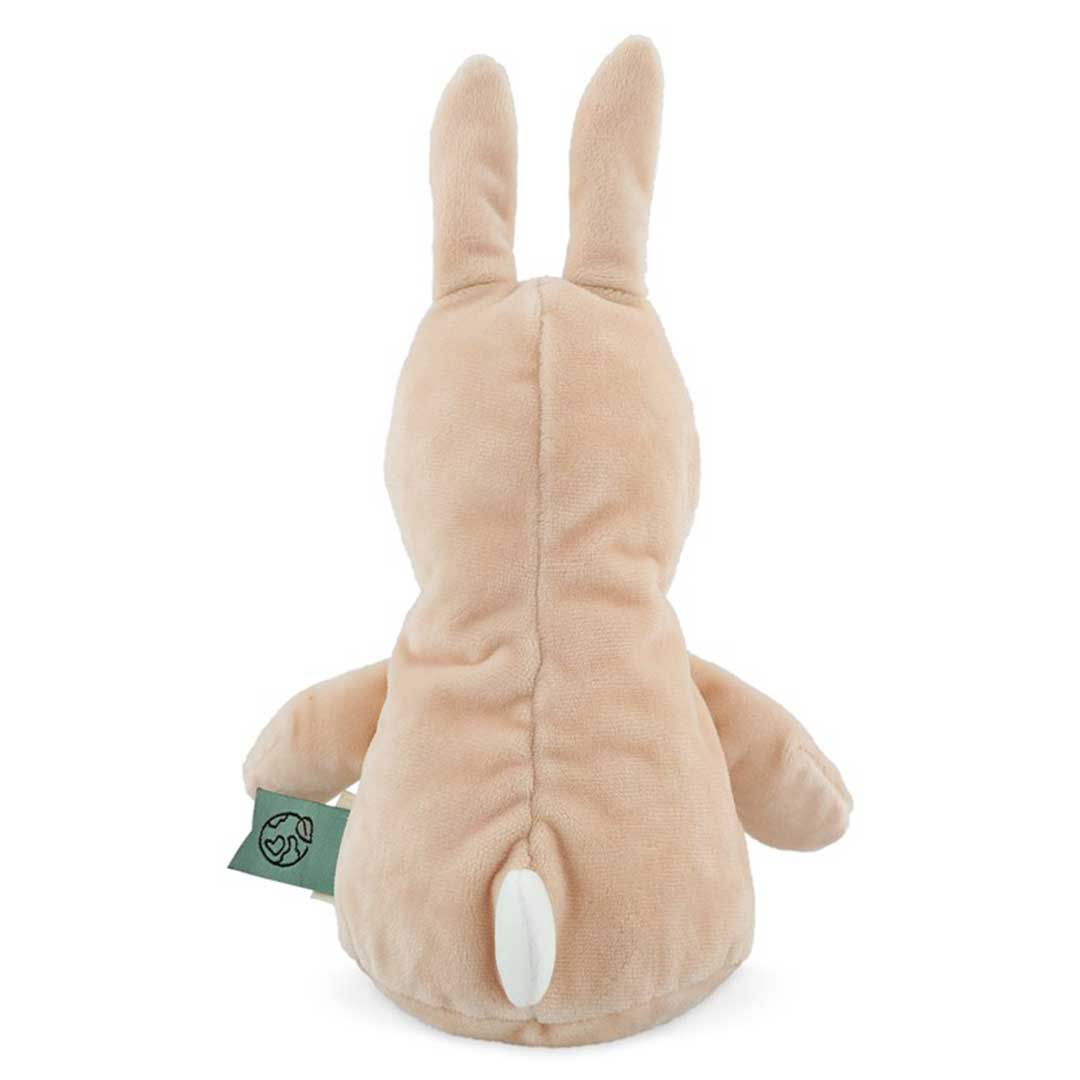 Vista posterior de un conejito de peluche beige con orejas largas, brazos pequeños y cola blanca. Una etiqueta verde está adjunta.