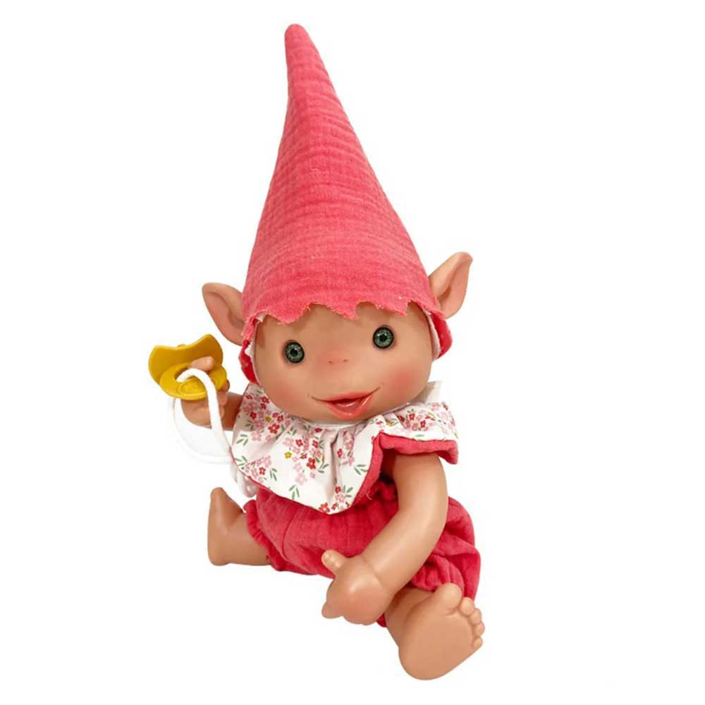Una muñeca, vestida de rojo, con un gorro puntiagudo y orejas grandes. Sostiene un chupete amarillo. La muñeca tiene ojos verdes y una cara sonriente.