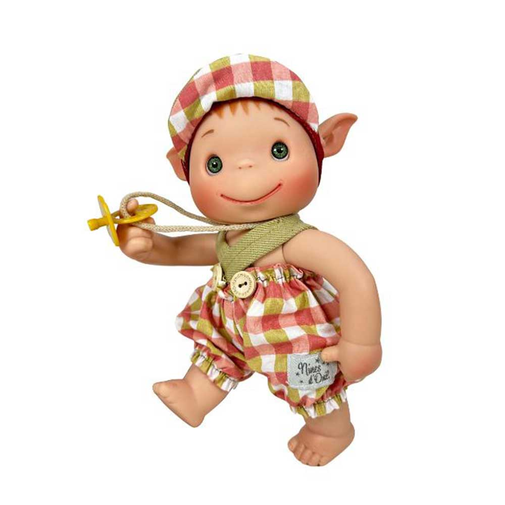 Una muñeca con ojos verdes, sombrero y pantalones cortos a cuadros, sosteniendo un chupete. La muñeca tiene orejas de elfo y una expresión sonriente.
