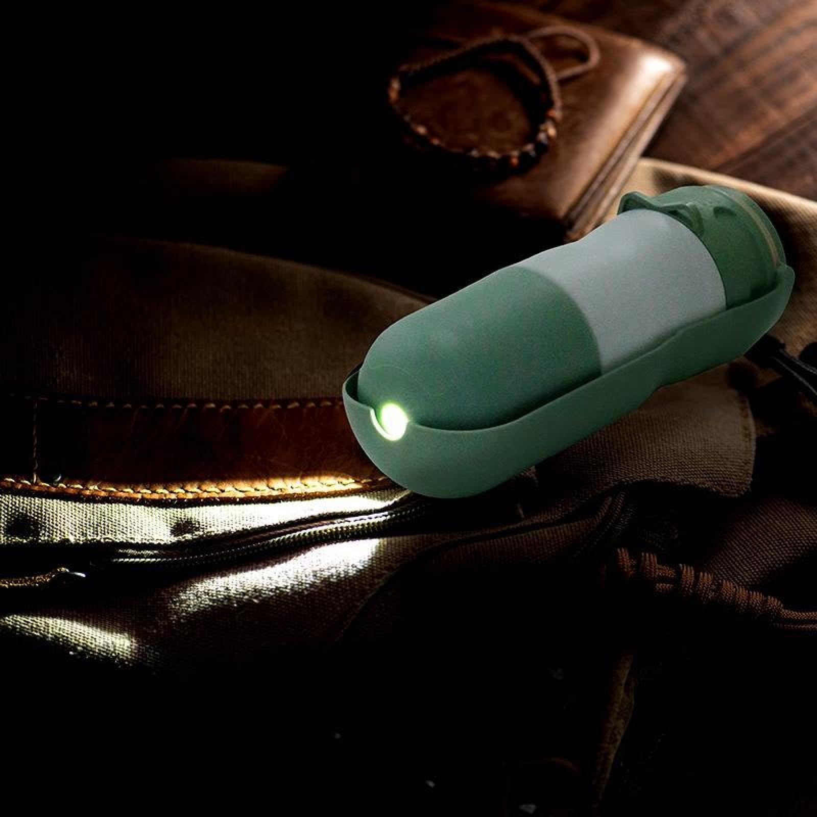 Eine grüne und weiße Taschenlampe beleuchtet eine dunkle Szene. Ein Hut, eine Lederbrieftasche und ein Armband sind im Hintergrund.