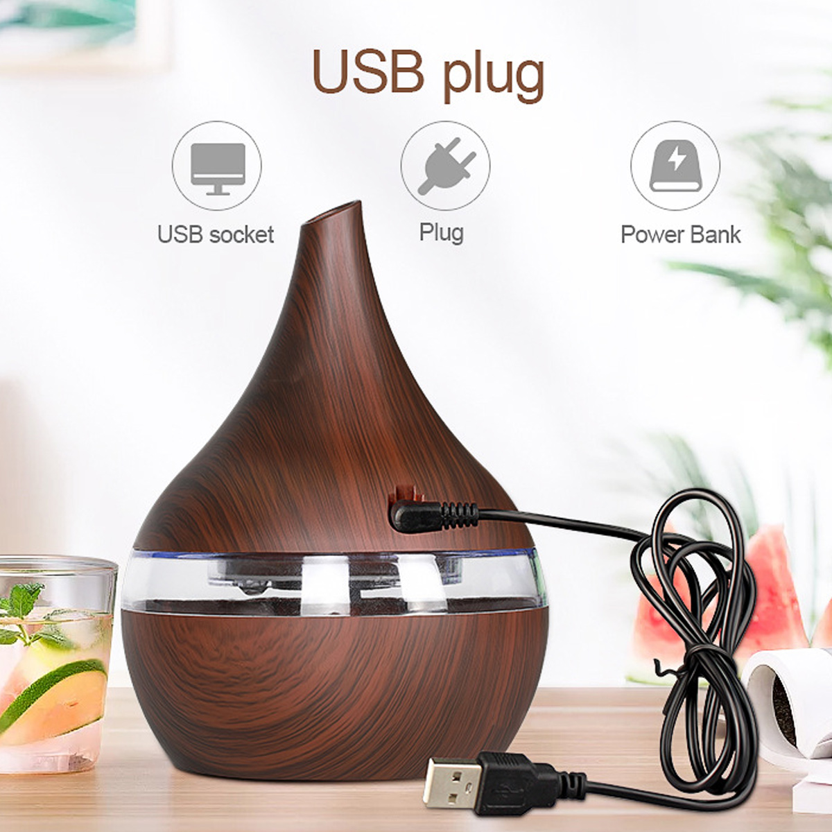 Ein hölzerner Aromadiffusor mit USB-Kabel. Links ein Glas Wasser mit Zitrone und Minze.