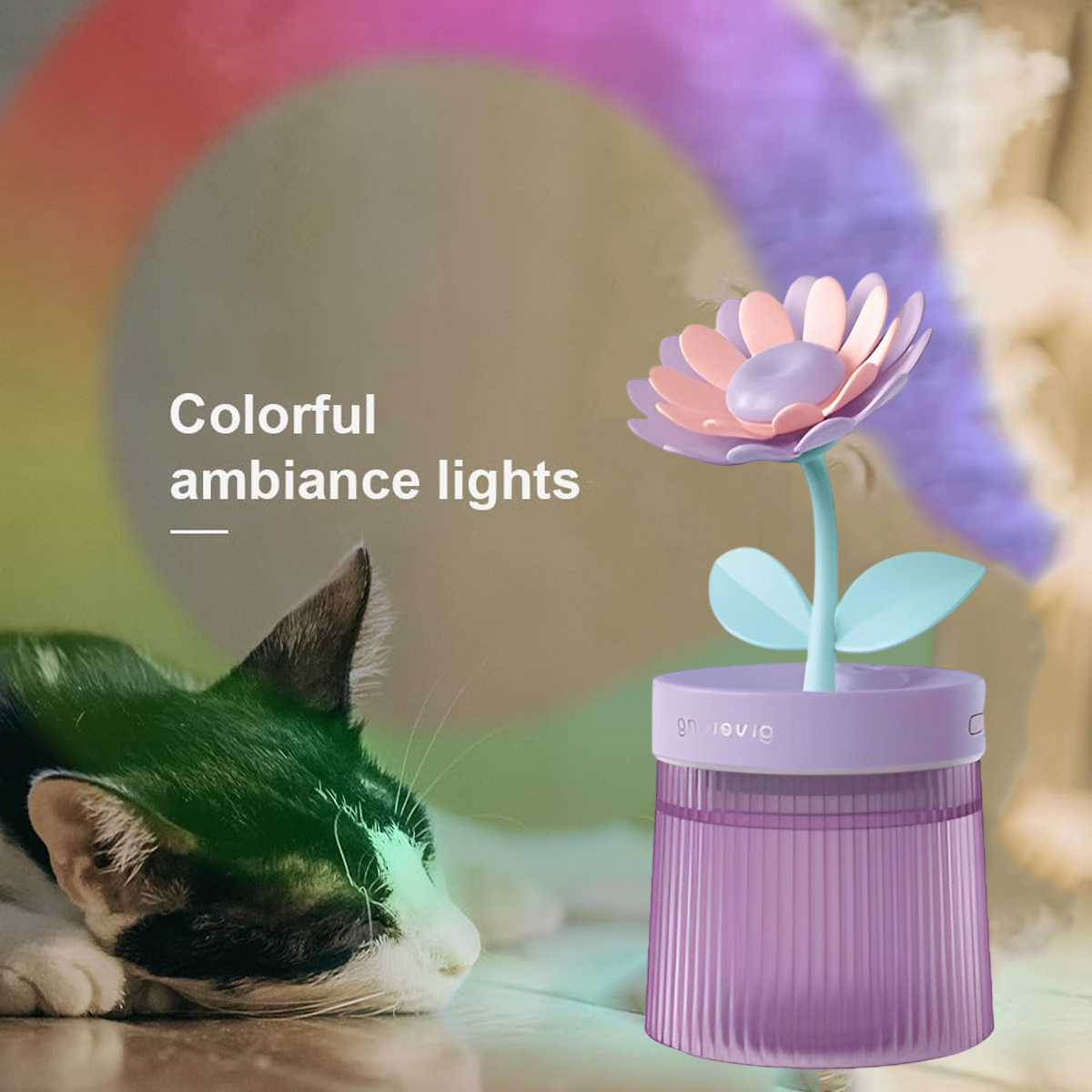 Eine Katze neben einer blumenförmigen Lampe. Die Lampe hat einen lila Sockel, hellrosa Blütenblätter und einen blauen Stiel. Im Hintergrund sind bunte Lichter.