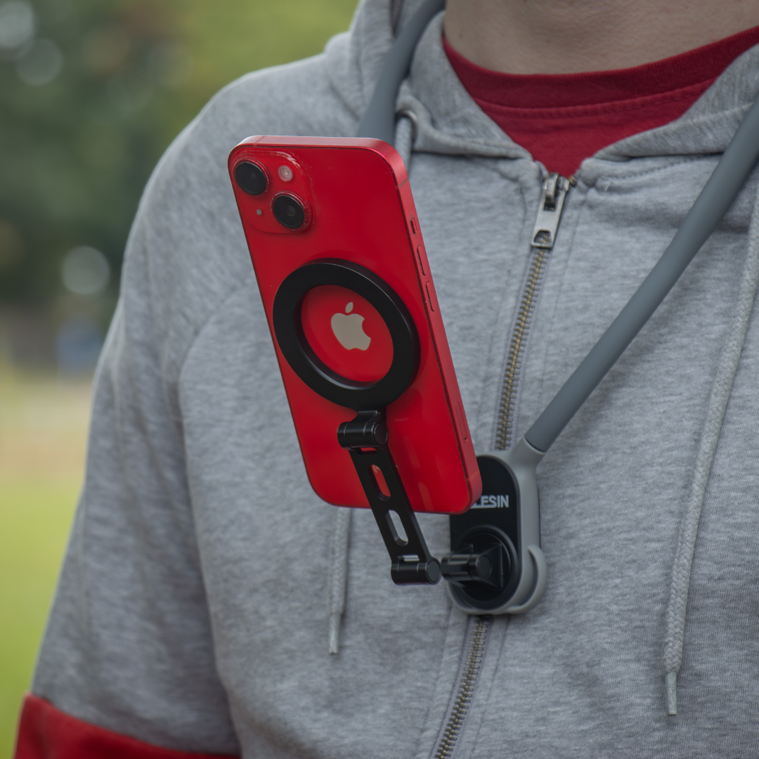 Eine Person trägt einen grauen Kapuzenpullover mit einem roten iPhone, das an einer Nackenhalterung befestigt ist. Das Telefon ist rot mit einem schwarzen Kreis um das Apple-Logo.