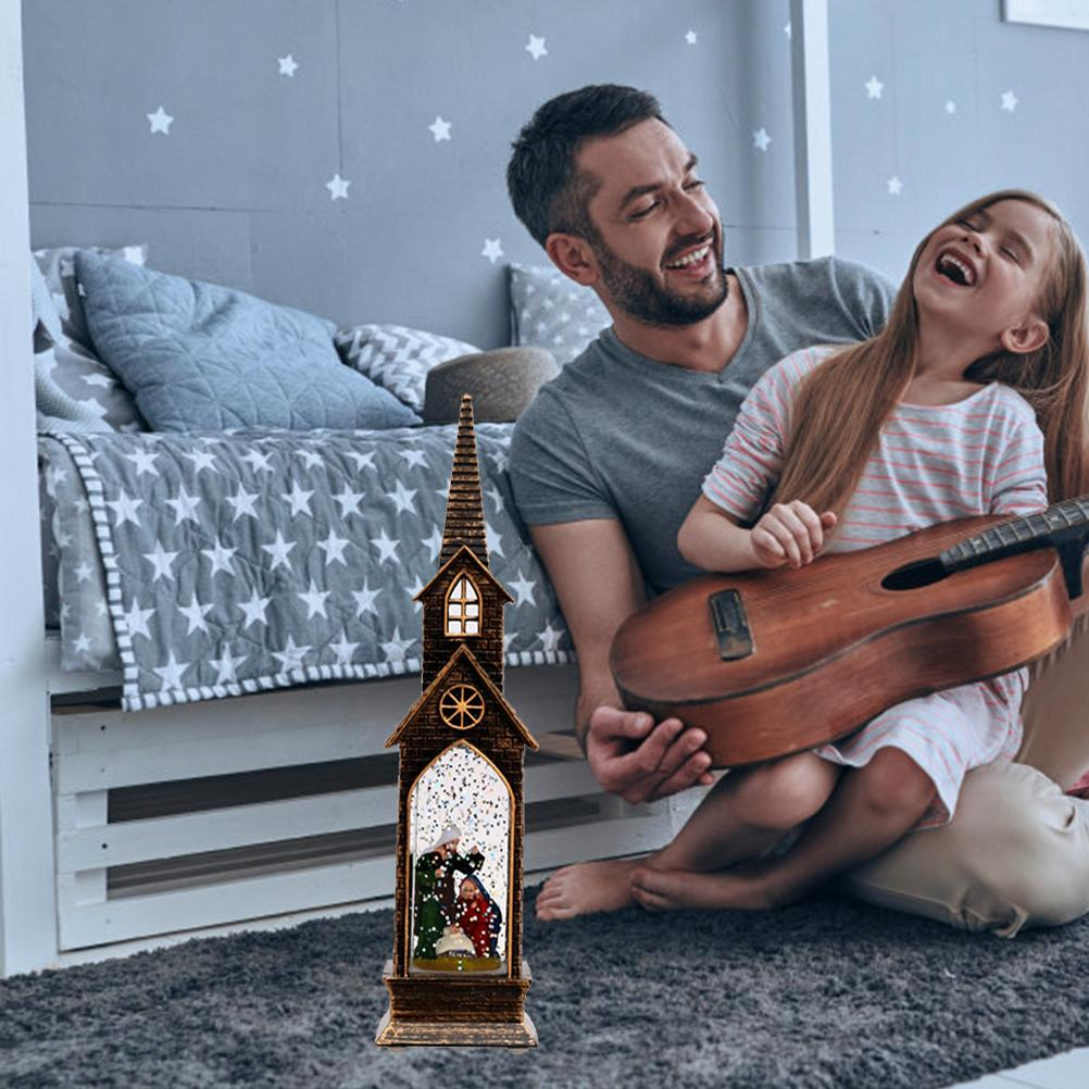 Ein Mann und ein Mädchen lachen, während das Mädchen eine Gitarre hält. Eine Kirchendekoration mit Schnee ist im Vordergrund.
