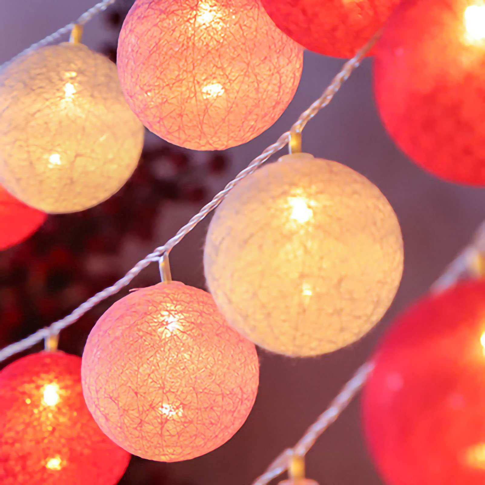 Nahaufnahme von Lichterketten. Viele runde, beleuchtete, dekorative Lichter in Rot, Orange und Gelb. Einige sind fokussiert, andere unscharf.