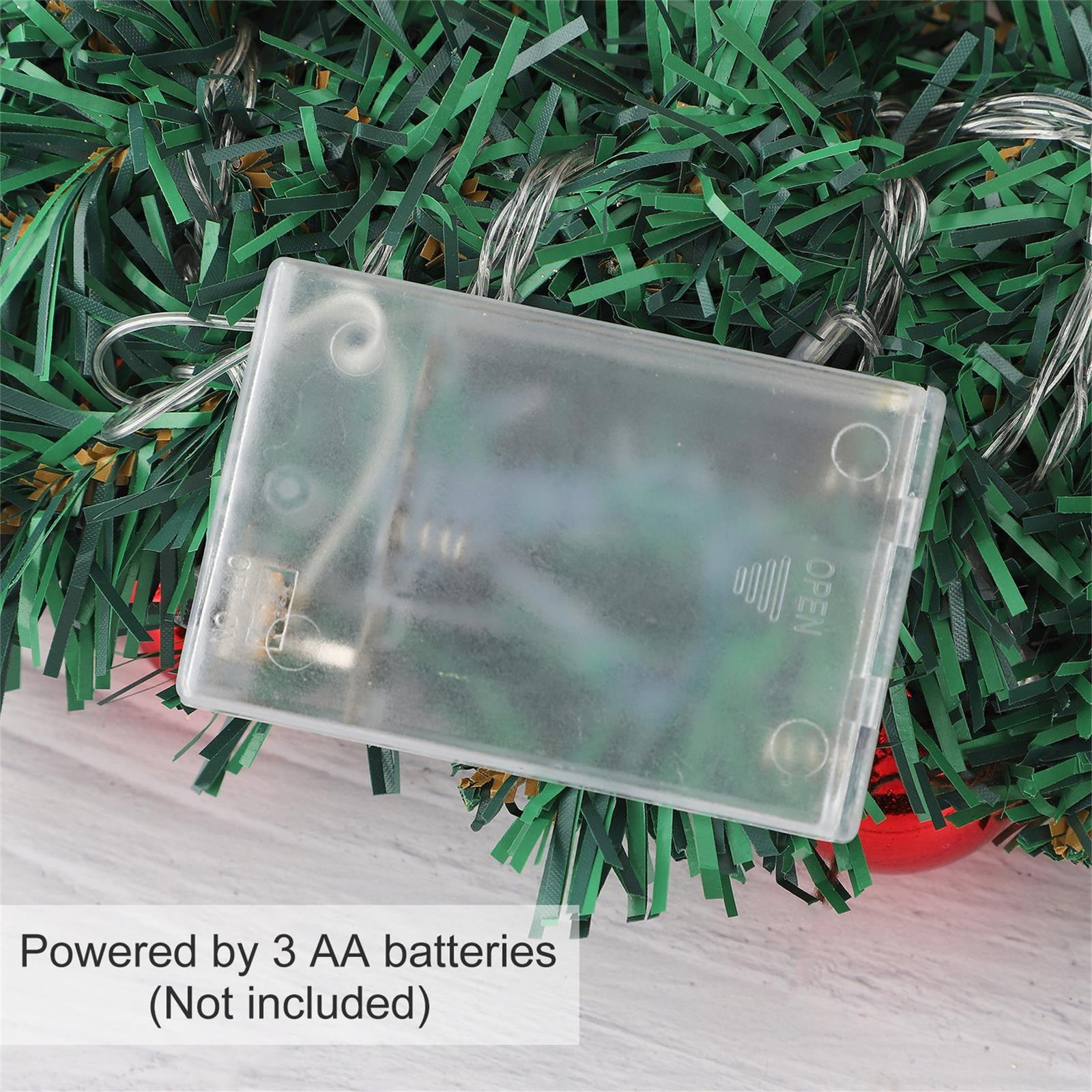 Transparente Batteriebox mit grünem Hintergrund. Text: Stromversorgung durch 3 AA-Batterien (nicht enthalten).